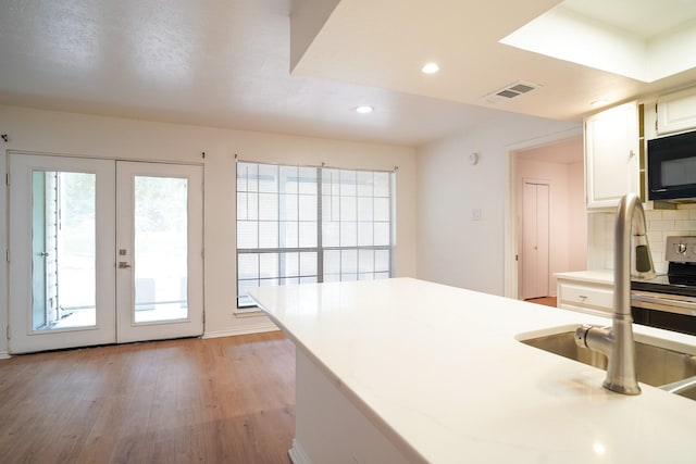 kitchen with french doors, sink, light hardwood / wood-style floors, decorative backsplash, and white cabinets