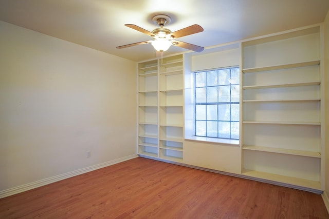 spare room featuring hardwood / wood-style flooring, built in features, and ceiling fan