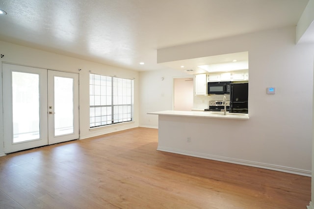 kitchen featuring light hardwood / wood-style flooring, white cabinetry, backsplash, black appliances, and kitchen peninsula