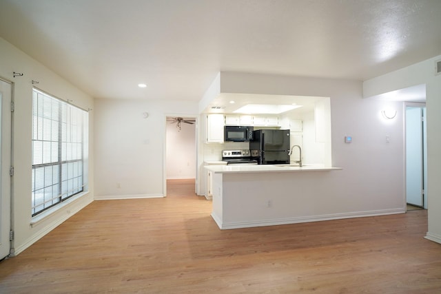 kitchen featuring white cabinetry, backsplash, black appliances, and light wood-type flooring