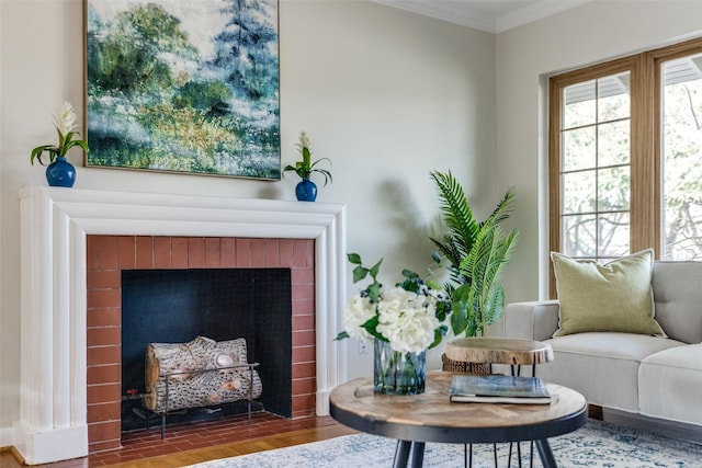 living area featuring a brick fireplace, hardwood / wood-style flooring, and ornamental molding