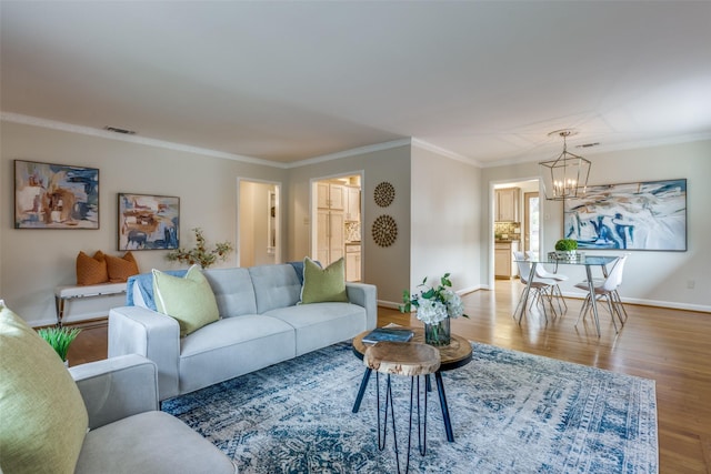 living room featuring ornamental molding, hardwood / wood-style floors, and an inviting chandelier