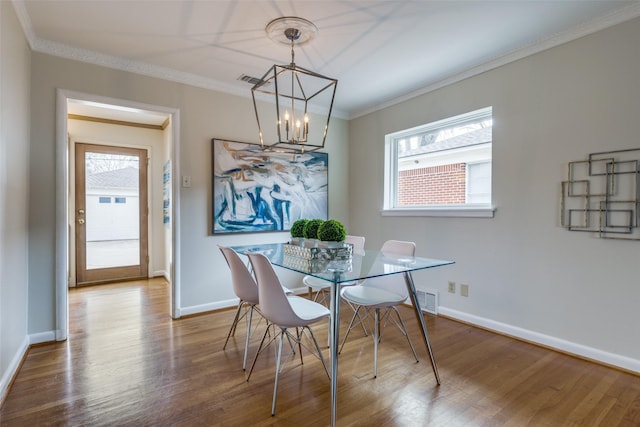 dining area with crown molding, hardwood / wood-style floors, and a notable chandelier