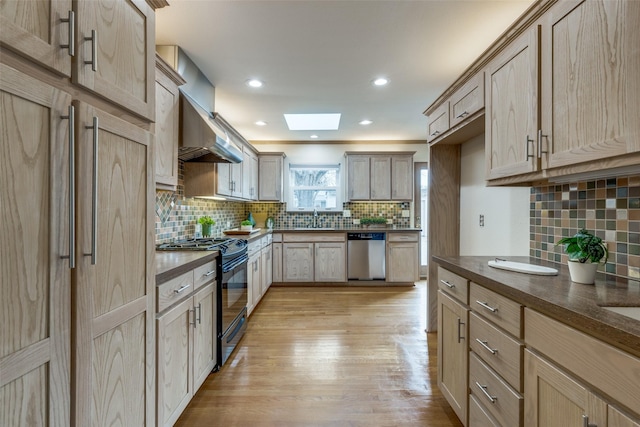 kitchen with a skylight, sink, stainless steel dishwasher, gas stove, and light brown cabinets