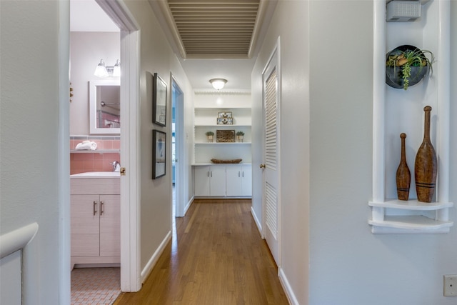 hallway with sink, built in features, and light wood-type flooring