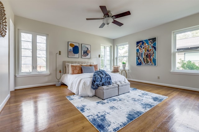 bedroom with multiple windows, hardwood / wood-style floors, and ceiling fan