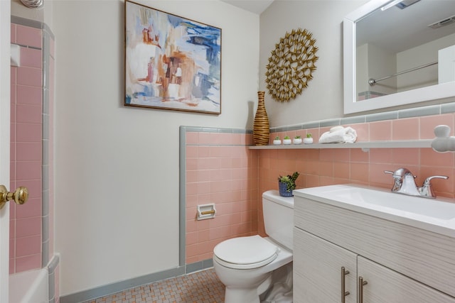 bathroom with tile patterned floors, vanity, toilet, and tile walls