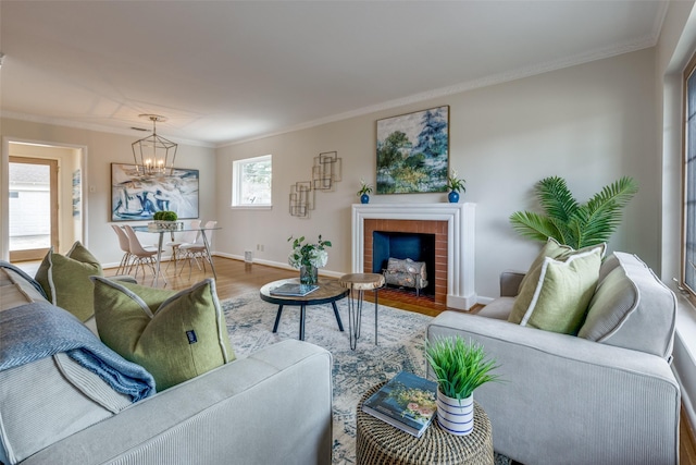 living room featuring hardwood / wood-style flooring, crown molding, a brick fireplace, and a notable chandelier