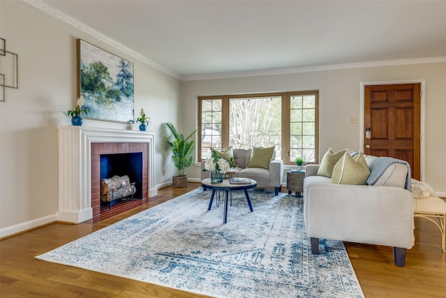 living room featuring hardwood / wood-style floors, ornamental molding, and a brick fireplace