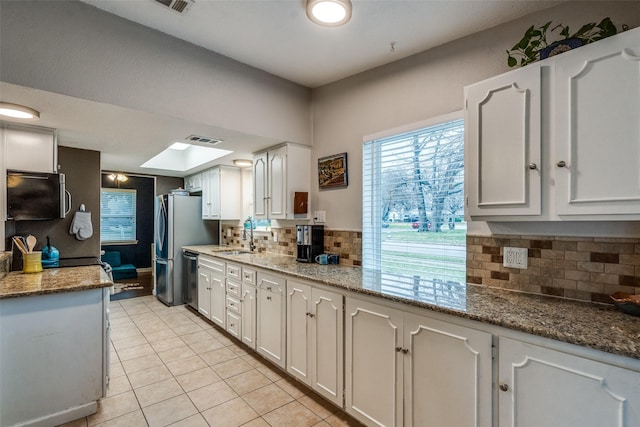 kitchen featuring sink, dishwasher, light stone counters, white cabinets, and light tile patterned flooring