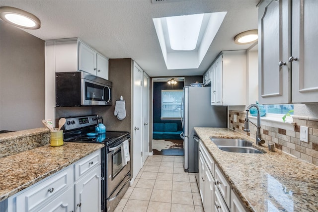 kitchen featuring sink, appliances with stainless steel finishes, white cabinetry, tasteful backsplash, and a textured ceiling