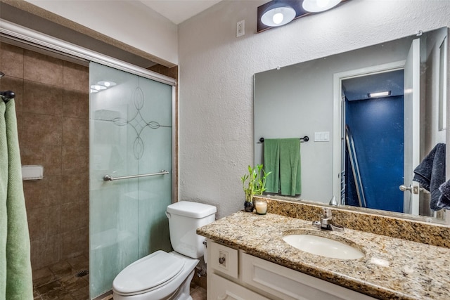 bathroom featuring vanity, a shower with shower door, and toilet