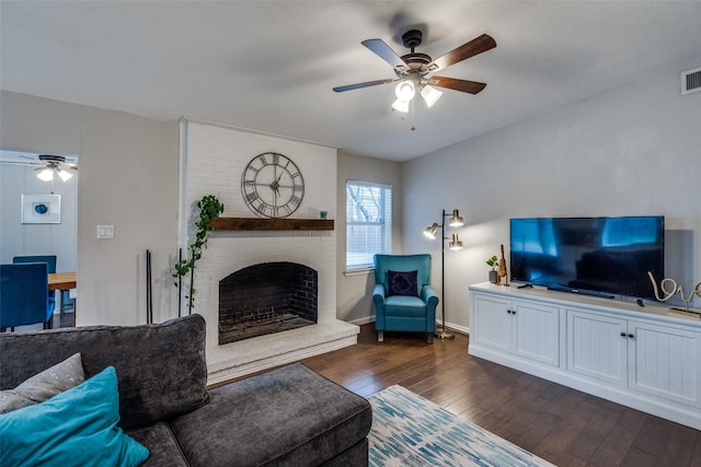 living room featuring ceiling fan, a fireplace, and dark hardwood / wood-style flooring