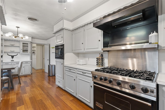 kitchen with wood-type flooring, luxury stove, hanging light fixtures, black microwave, and range hood