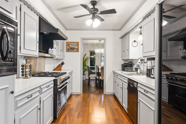 kitchen with sink, black appliances, ornamental molding, hardwood / wood-style flooring, and exhaust hood