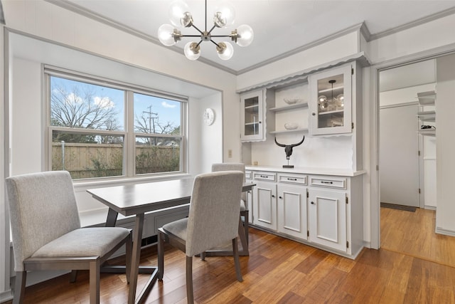 dining area featuring an inviting chandelier, crown molding, and light wood-type flooring