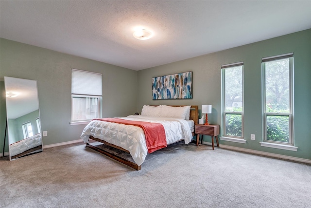 bedroom with carpet floors, multiple windows, and a textured ceiling