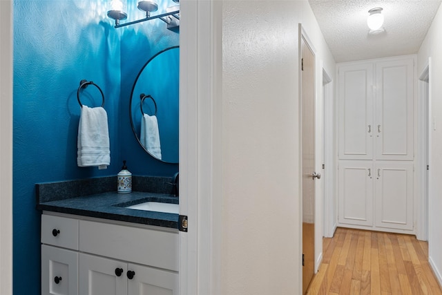 bathroom featuring hardwood / wood-style flooring, vanity, and a textured ceiling