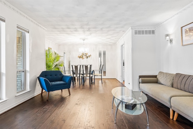 living room with a notable chandelier, hardwood / wood-style flooring, and ornamental molding