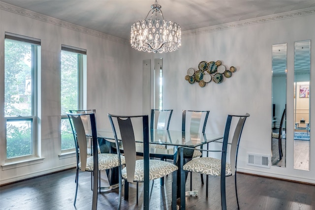 dining space with dark wood-type flooring, ornamental molding, and a notable chandelier