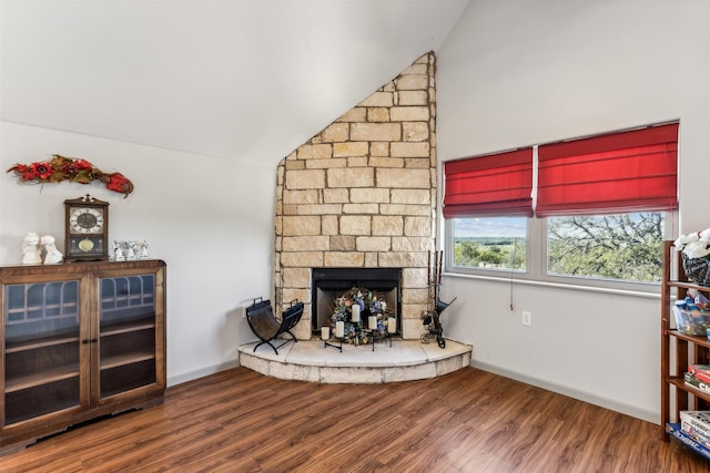 living room with a stone fireplace, vaulted ceiling, and hardwood / wood-style flooring