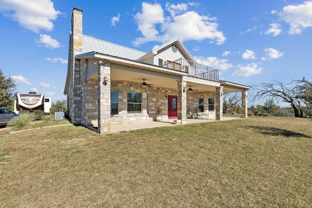 rear view of property featuring ceiling fan, a yard, a balcony, and a patio area