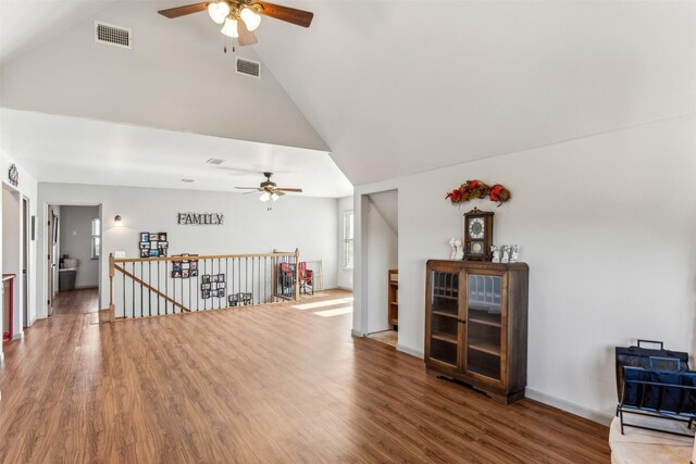 empty room with hardwood / wood-style flooring, ceiling fan, and high vaulted ceiling