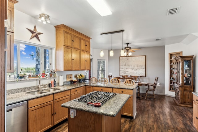 kitchen with sink, appliances with stainless steel finishes, kitchen peninsula, a kitchen island, and pendant lighting