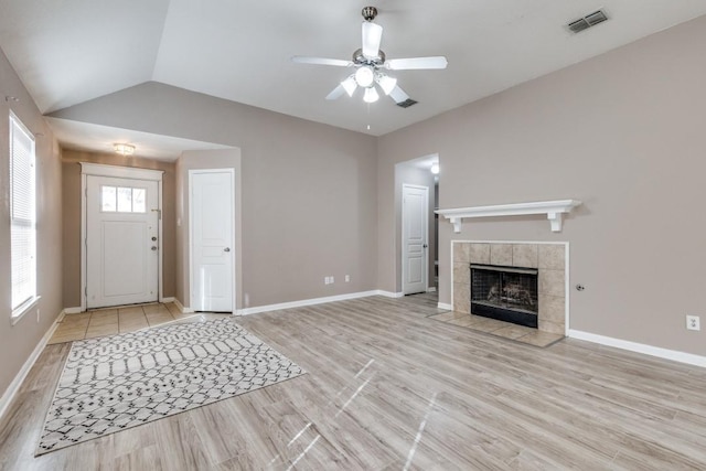 unfurnished living room with lofted ceiling, a fireplace, ceiling fan, and light wood-type flooring