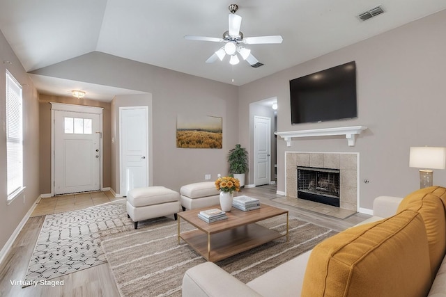 living room featuring lofted ceiling, a fireplace, light hardwood / wood-style floors, and ceiling fan