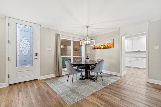 dining space featuring ornamental molding, an inviting chandelier, and light hardwood / wood-style flooring