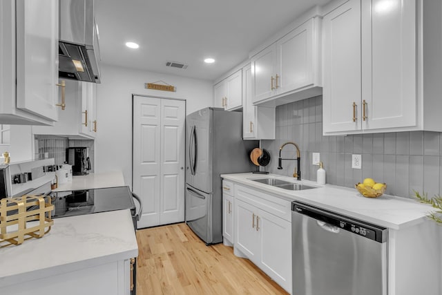 kitchen featuring sink, white cabinetry, light stone counters, stainless steel appliances, and backsplash