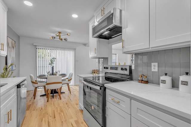 kitchen with stainless steel appliances, light stone countertops, and white cabinets