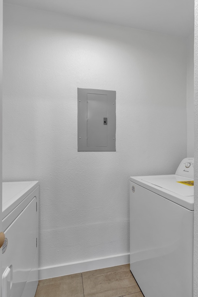 clothes washing area with electric panel, washer and clothes dryer, and light hardwood / wood-style flooring