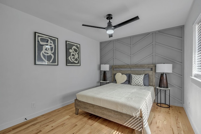 bedroom featuring ceiling fan, light hardwood / wood-style floors, and multiple windows