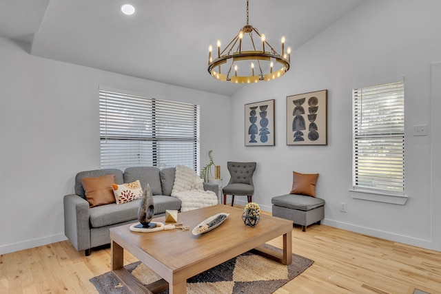 living room featuring an inviting chandelier, vaulted ceiling, and light wood-type flooring