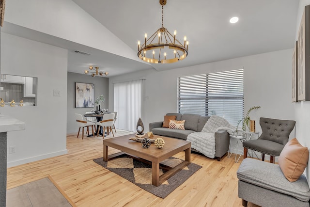 living room with vaulted ceiling, a chandelier, and light wood-type flooring