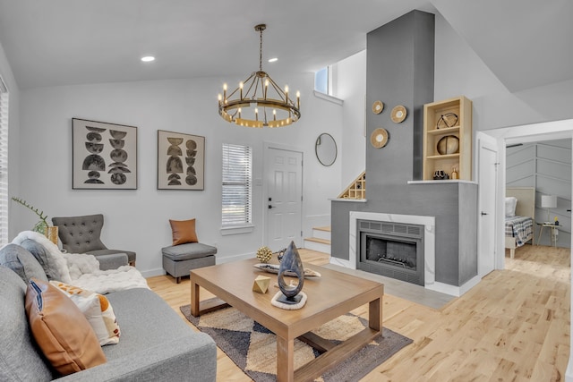 living room with an inviting chandelier, vaulted ceiling, light hardwood / wood-style floors, and plenty of natural light