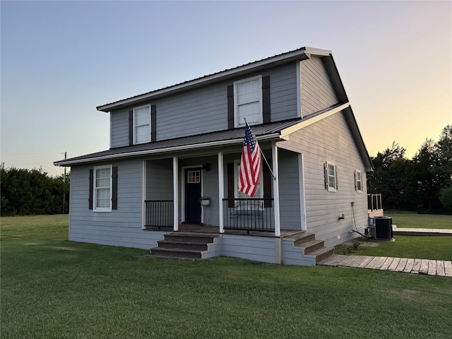 view of front of home featuring a yard, cooling unit, and covered porch