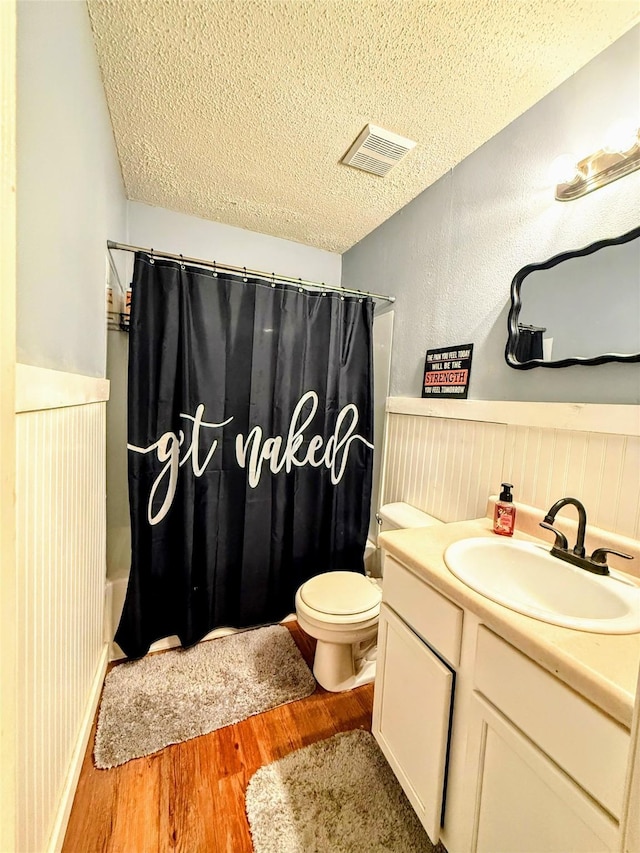 full bathroom with hardwood / wood-style flooring, shower / tub combo with curtain, vanity, and a textured ceiling