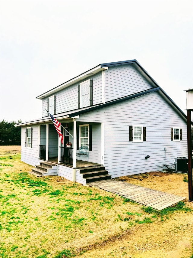 rear view of property with covered porch, a lawn, and central air condition unit