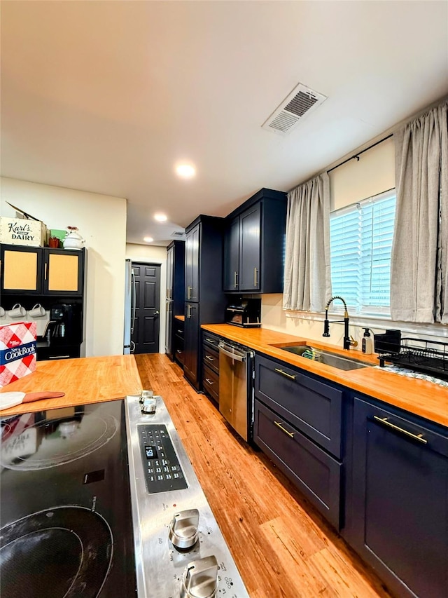 kitchen with stainless steel dishwasher, wooden counters, and sink