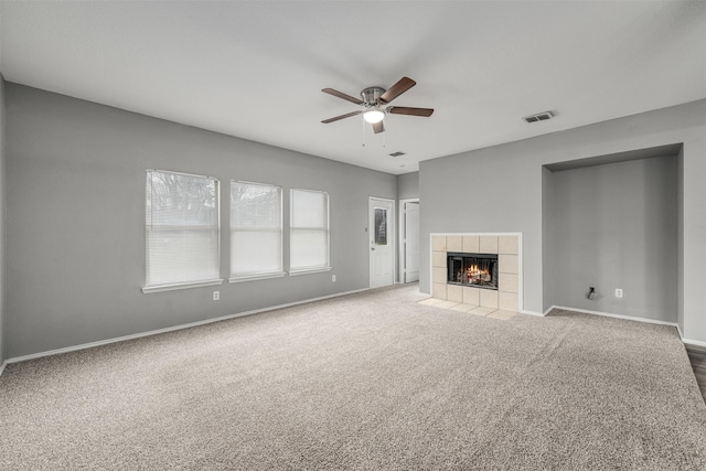 unfurnished living room with a tile fireplace, ceiling fan, and carpet