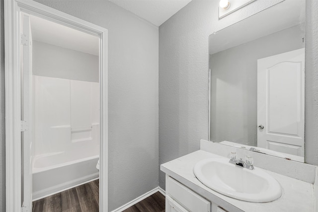 full bathroom with vanity, hardwood / wood-style flooring, shower / bathtub combination, and toilet