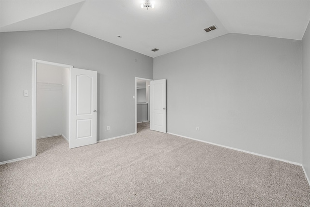 unfurnished bedroom featuring lofted ceiling, a spacious closet, carpet, and a closet