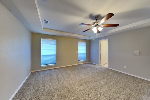 empty room featuring light colored carpet, a raised ceiling, and ceiling fan