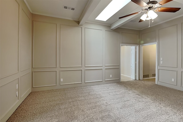 carpeted spare room featuring beam ceiling, ornamental molding, and ceiling fan