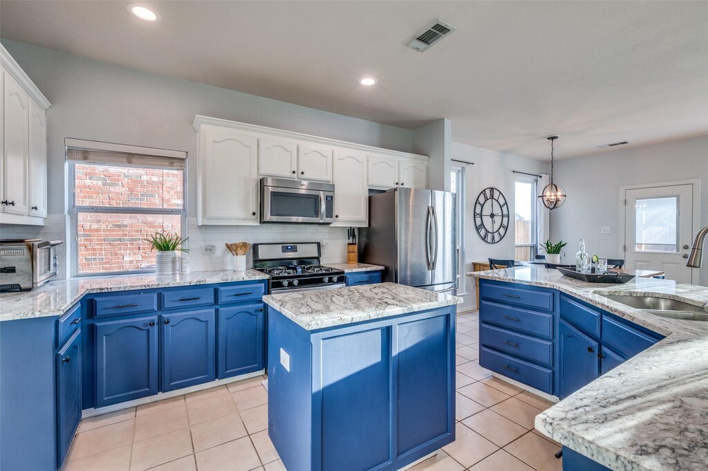 kitchen featuring appliances with stainless steel finishes, white cabinetry, blue cabinets, a kitchen island, and decorative light fixtures