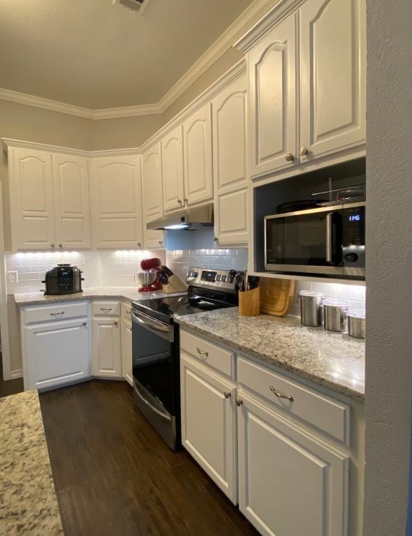 kitchen featuring dark wood-type flooring, appliances with stainless steel finishes, white cabinetry, backsplash, and light stone counters