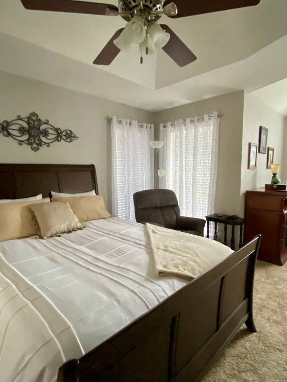 carpeted bedroom featuring a raised ceiling and ceiling fan